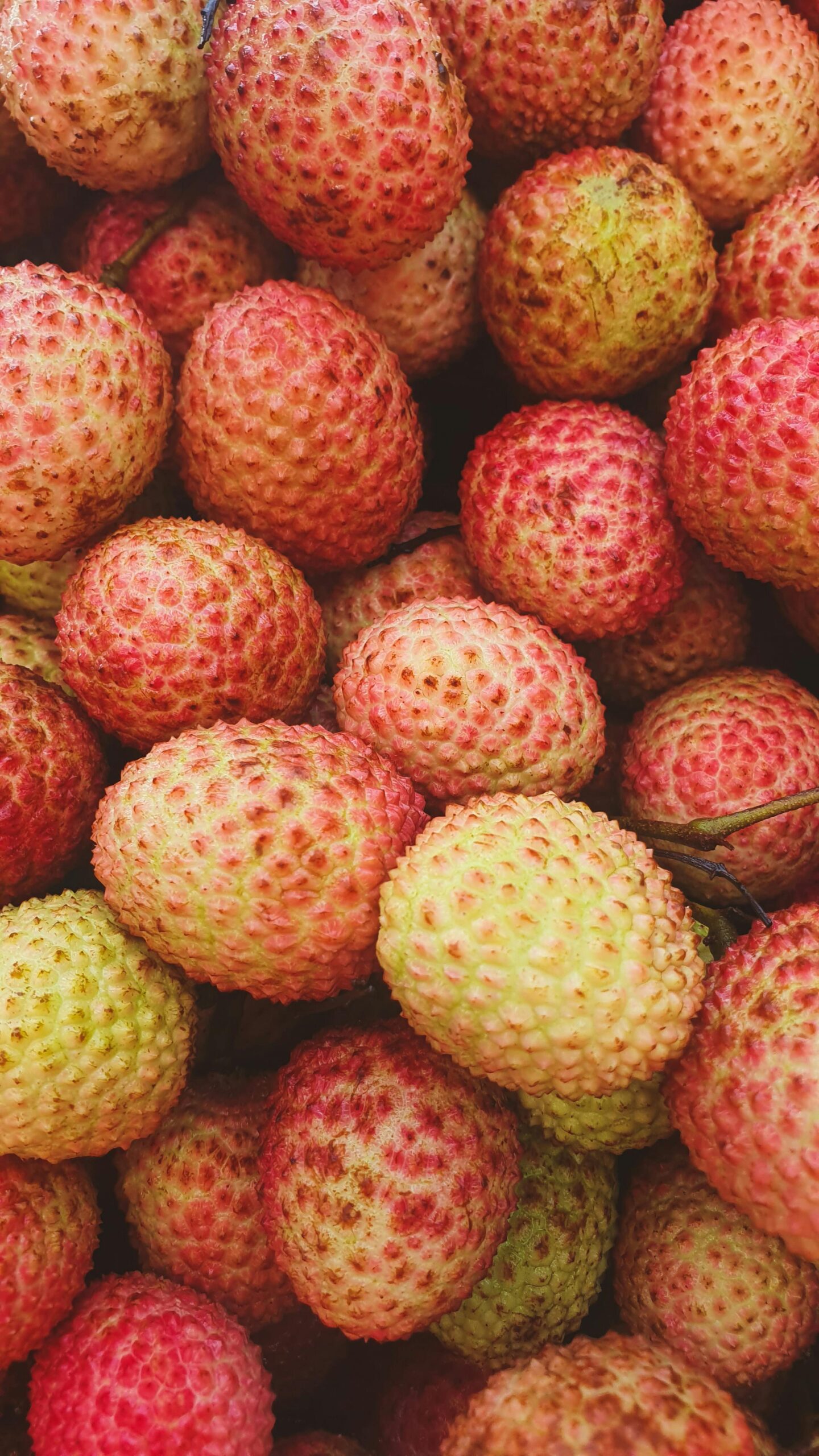 Vibrant close-up of a pile of fresh lychees, showcasing their natural texture and colors.