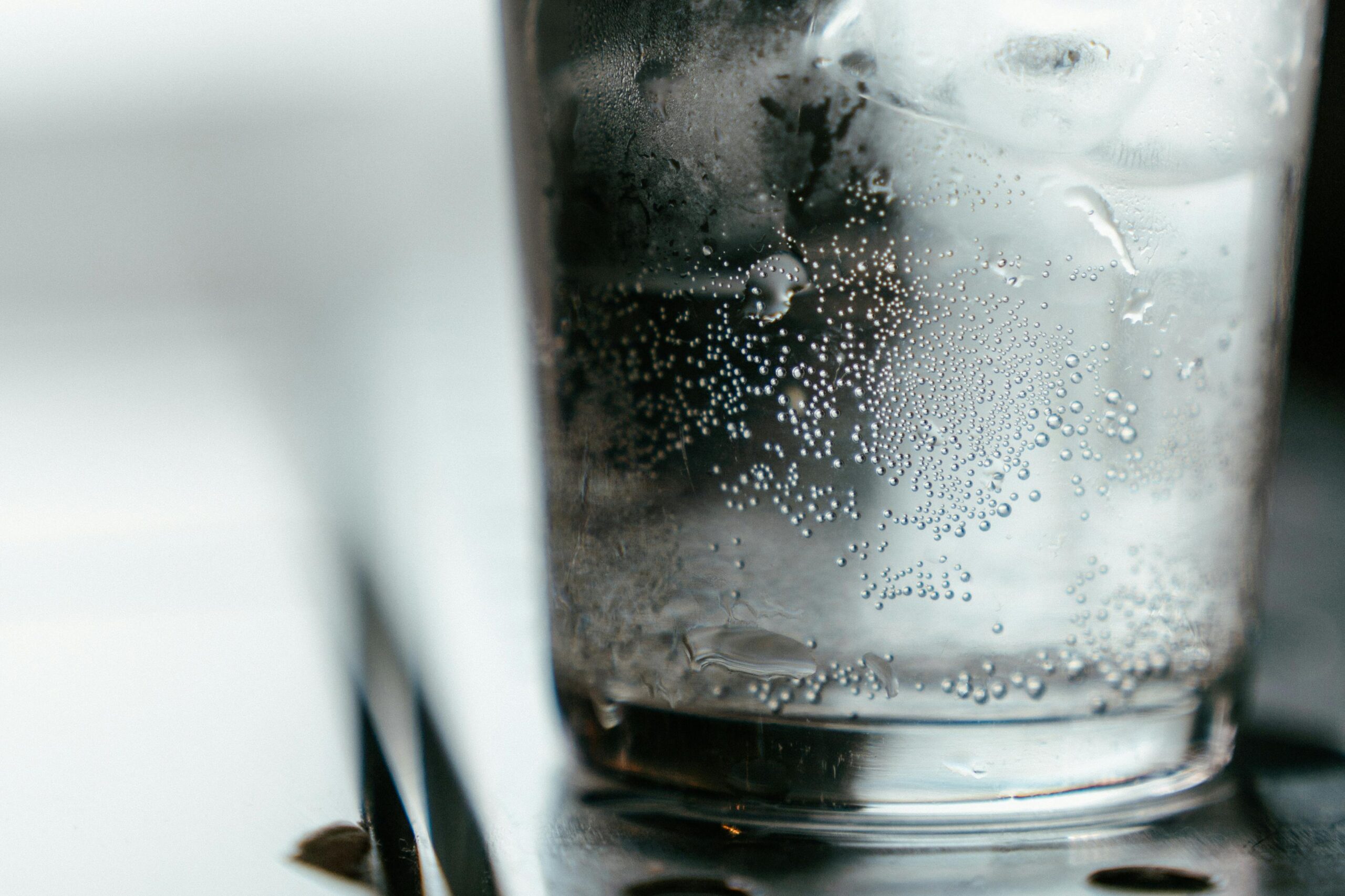 Refreshing ice water with bubbles in a glass, close-up shot with copy space.